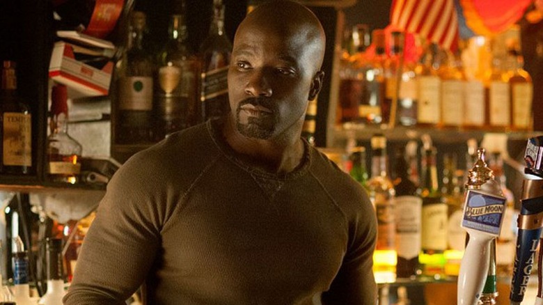 man in a brown shirt behind a bar next to beer taps