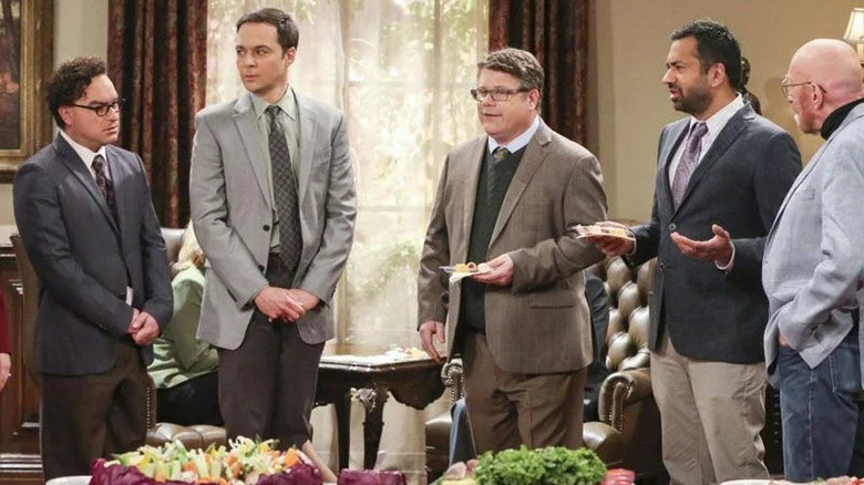 Sheldon, Dr. Pemberton, and others at a party, holding plates of food and wearing ties