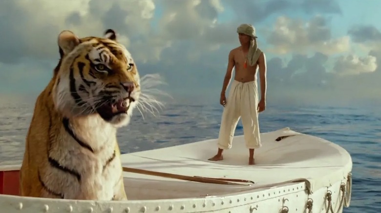 Suraj Sharma's Pi stands on a boat while his tiger passenger roars in the foreground in Life of Pi