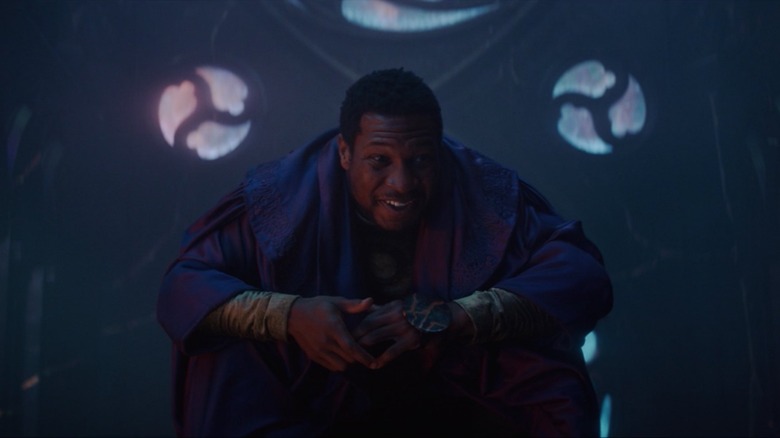 A crouching Jonathan Majors smiles