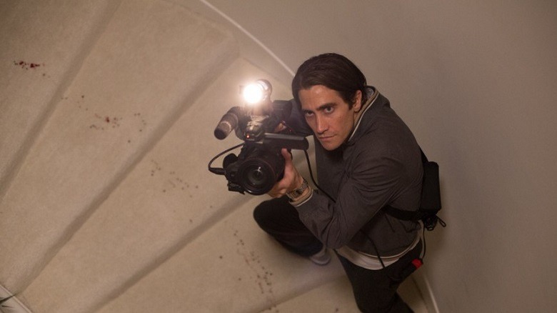 Louis Bloom holding a camera up to a unfolding crime scene