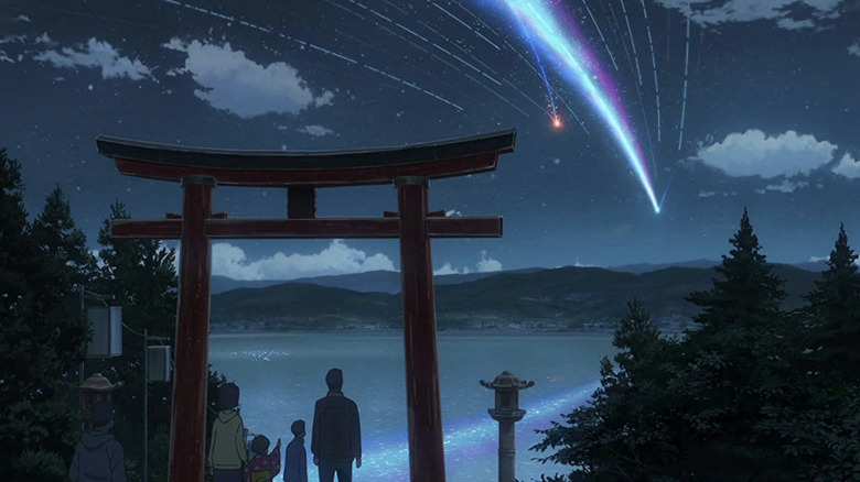 A shooting star falling across the sky in front of a shrine entrance