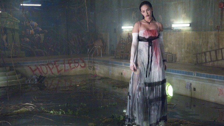 Jennifer stands in a pool wearing a bloody dress