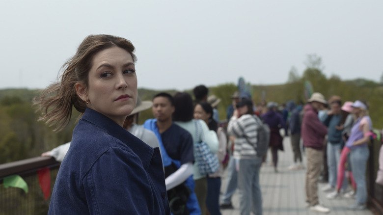 Molly looks over shoulder on a crowded bridge 