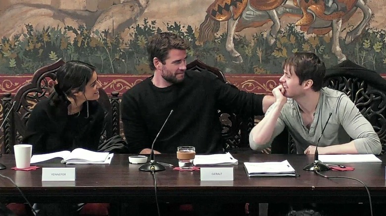 Anya Chalotra, Liam Hemsworth e Joey Batey em uma mesa lendo para a 4ª temporada de The Witcher.