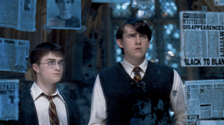 Harry and Neville looking at newspapers and pictures in Harry Potter and the Order of the Phoenix