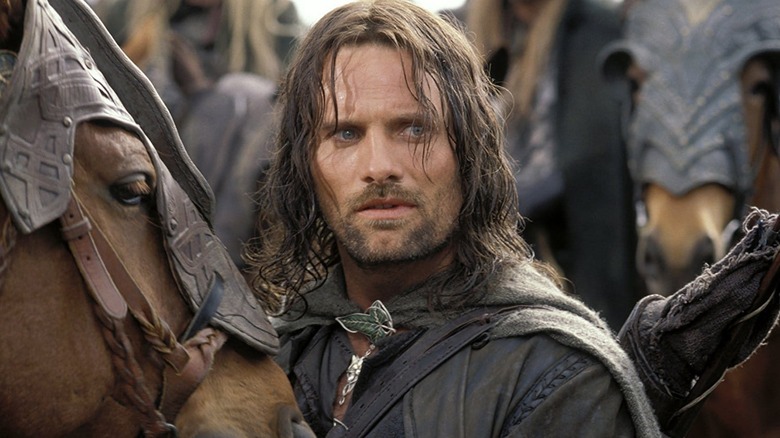 Aragorn parado ao lado de um cavalo