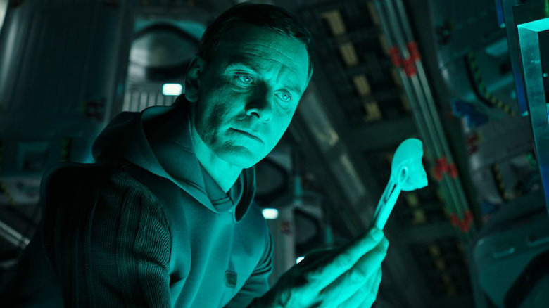 Michael Fassbender inspecting an object in Alien: Covenant