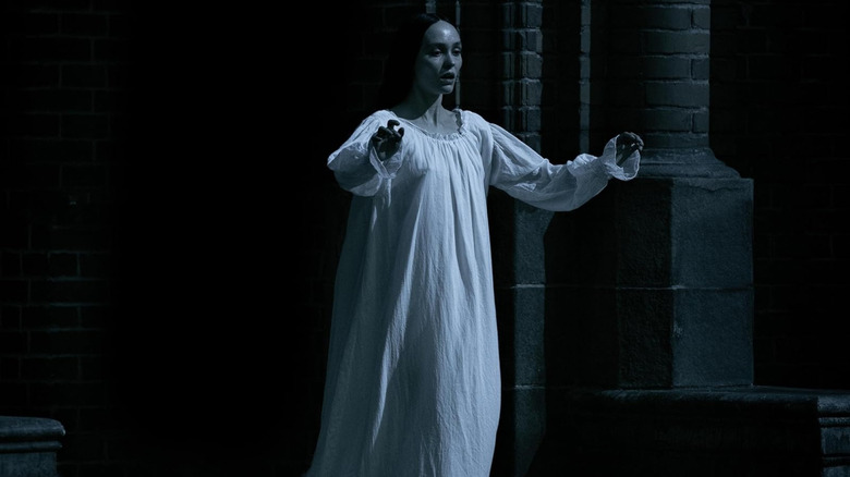 Lily-Rose Depp as Ellen walking in her gown at night in Nosferatu