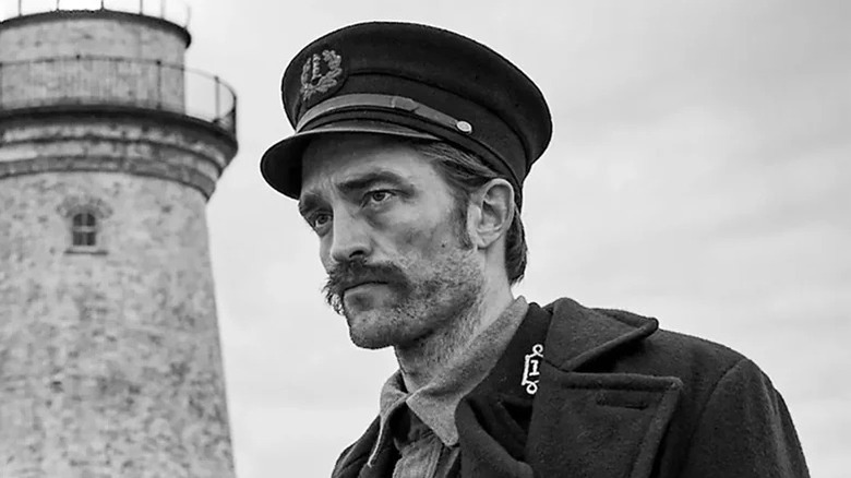 Robert Pattinson's Ephraim Winslow/Thomas Howard stands outside his lighthouse looking off into the distance in The Lighthouse