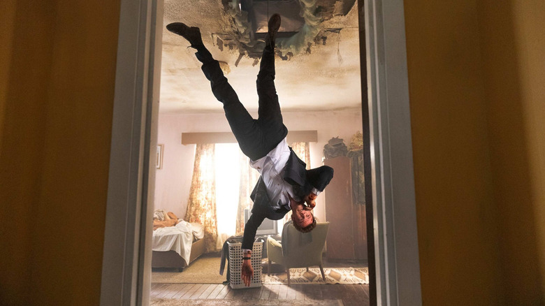 Nathan Caine (Jack Quaid) dangles upside down while making a phone call in Novocaine