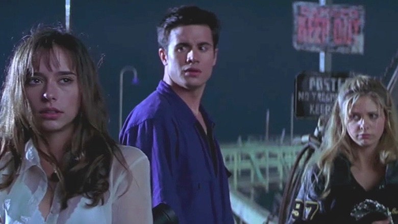 Jennifer Love Hewitt, Freddie Prinze Jr., and Sarah Michelle Gellar stand on the docks looking concerned in I Know What You Did Last Summer