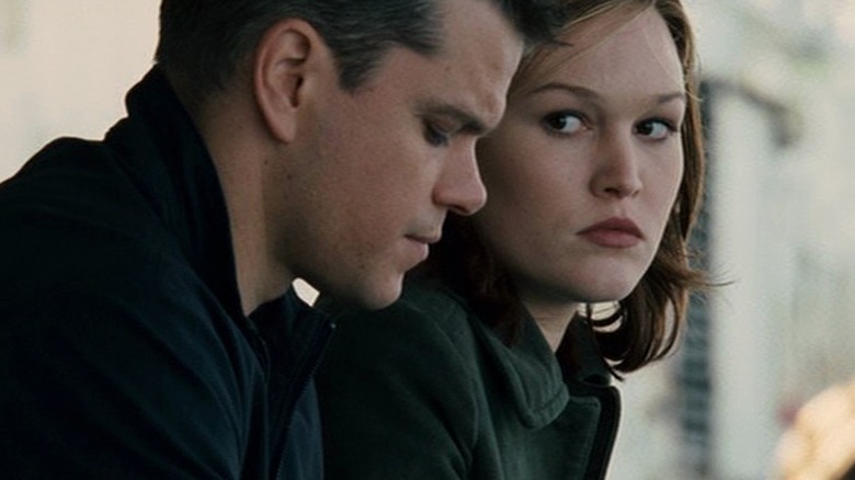 Nicky Parsons sits next to Jason Bourne and looks at him in The Bourne Ultimatum