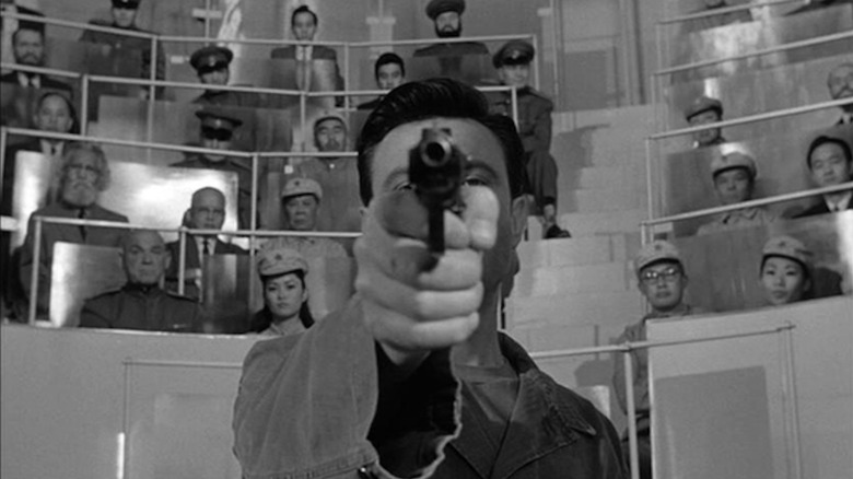 Lawrence Harvey points a pistol to the camera as Raymond Shaw in the Manchourian candidate