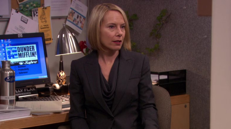 Holly at her desk, wearing black and looking at something off camera in The Office