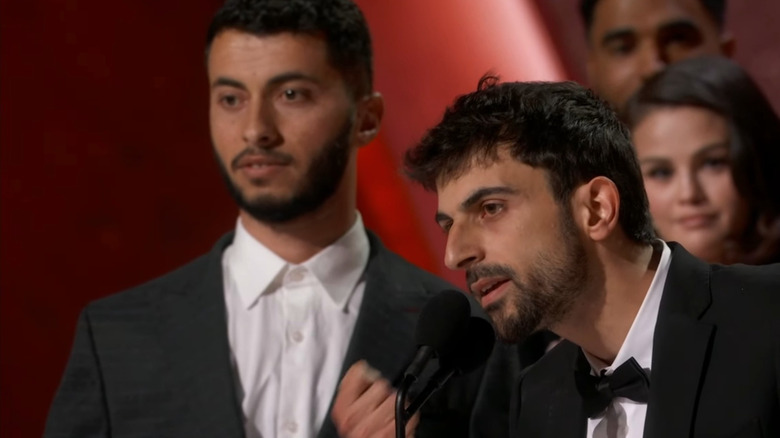 Yuval Abraham delivering a speech at the Oscars as Basel Adra listens in the background