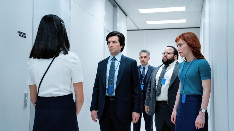 Sarah Bock as Ms. Huang, Adam Scott as Mark S., John Turturro as Irving B., Zach Cherry Dylan G., and Britt Lower as Helly R. crowded into a hallway in Severance