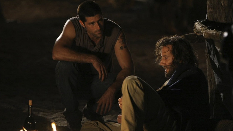 Jack crouches to talk to a drunken Desmond on the beach in Lost season 2