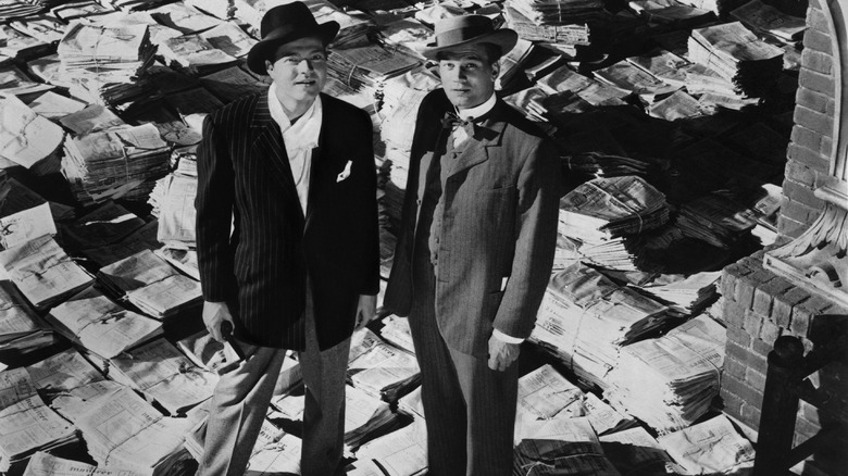 Orson Welles and Joseph Cotten stand amid newspapers