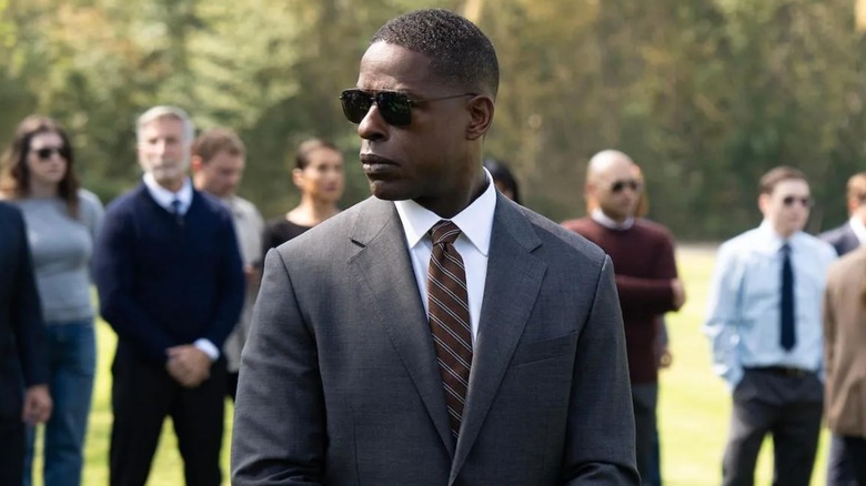 Xavier wearing glasses and a suit standing in front of a crowd on Paradise