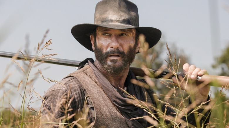 Dirt-covered cowboy in tall grass