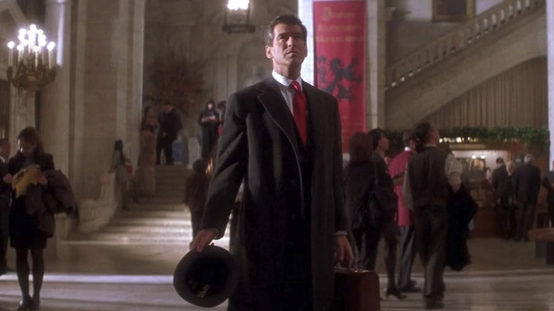 Pierce Brosnan looks up with a hat and briefcase in his hand as Thomas Crown in The Thomas Crown Affair