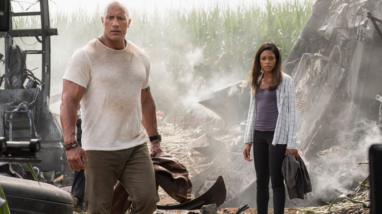 Dwayne Johnson's Davis and Naomie Harris' Kate sorting through the wreckage of the plane crash in Rampage (2018)