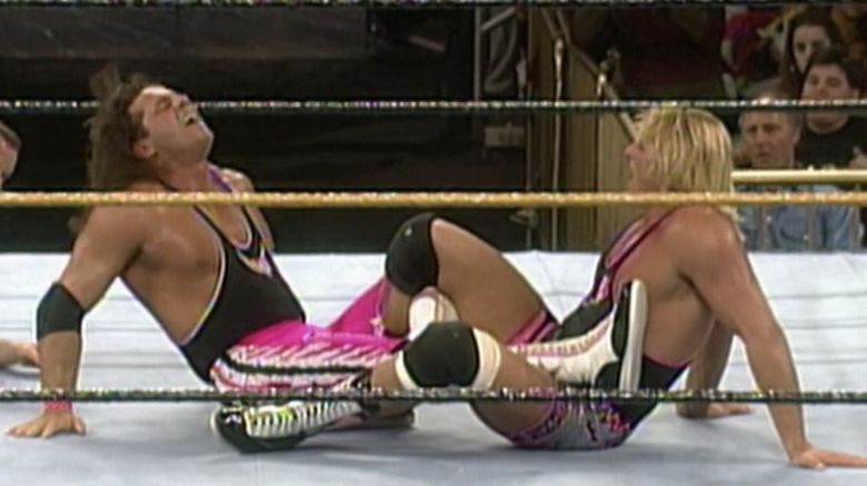 Owen Hart has Bret Hart locked up in a figure four leglock