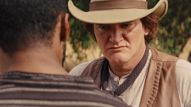 Quentin Tarantino as Frankie looks intrigued by what Django is saying in Django Unchained