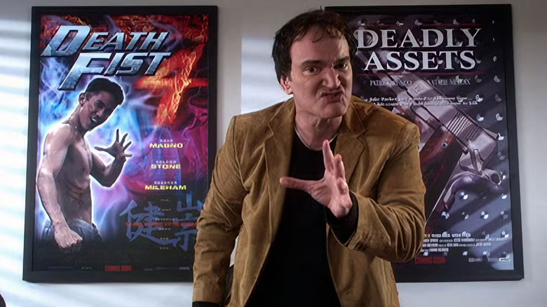 Quentin Tarantino parado frente a dos carteles de películas de acción en El mago de Oz de Los Muppets