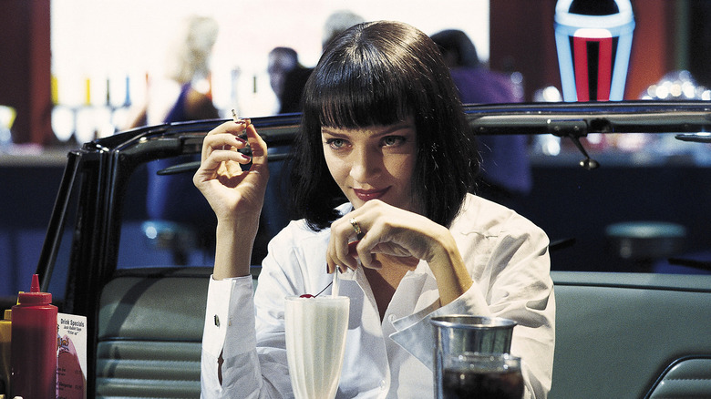 Mia Wallace sonríe mientras fuma Pulp Fiction