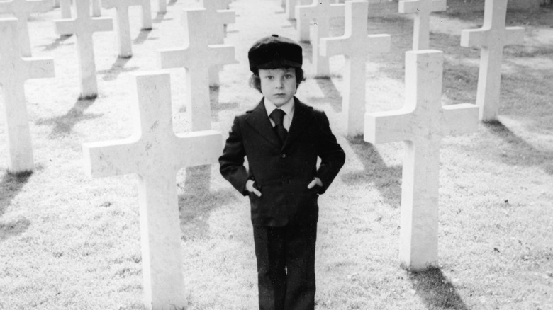 Damien standing in graveyard