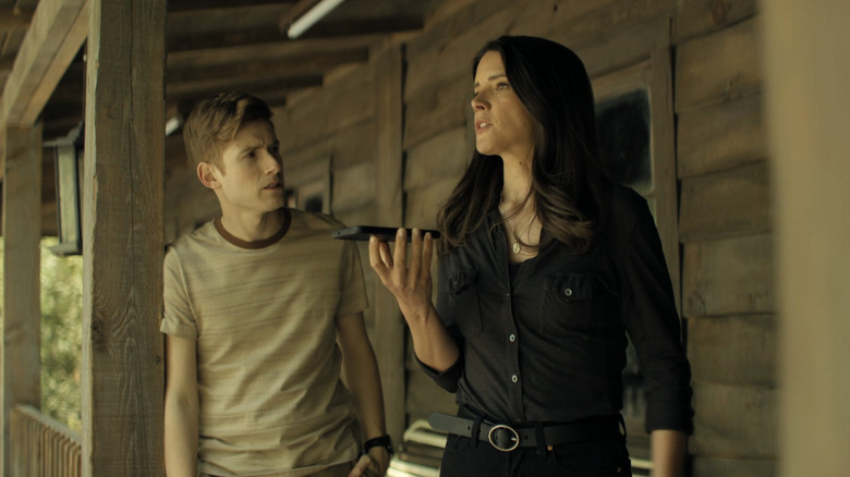 Daniel David Stewart's Steven Elliot looks as Sonya Cassidy's Susan Duffy as she talks on a phone in Reacher