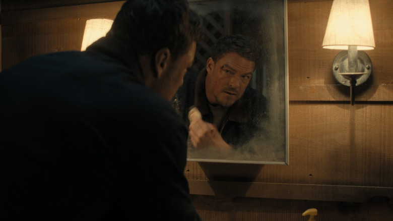 Alan Ritchson's Jack Reacher looks at himself in the mirror as he cleans a face wound in Reacher