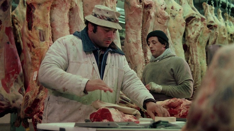 Burt Young as Paulie, showing Sylvester Stallone's Rocky how to pack meat