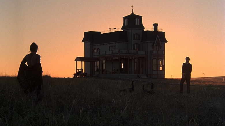 An old house, silhouetted by the sunset, flanked by lovers Bill and Abby, staring at each other in the growing shadows.