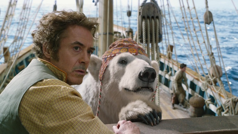 Dr. Dolittle, standing on the deck of a ship, next to a polar bear in a hat.