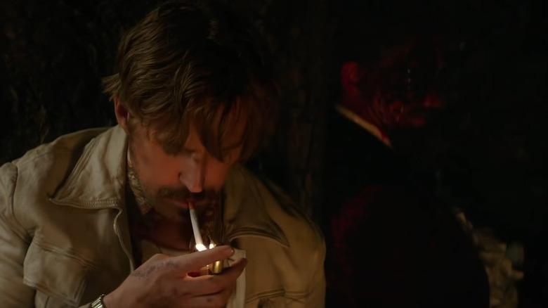 Ryan Gosling as Holland March lighting a cigarette in front Robert Downey Jr. as a very dead Sid Shattuck in The Nice Guys