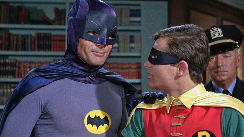 Batman tersenyum pada Robin di kantor Komisaris Gordon, sebuah adegan dari seri 1966 Batman.