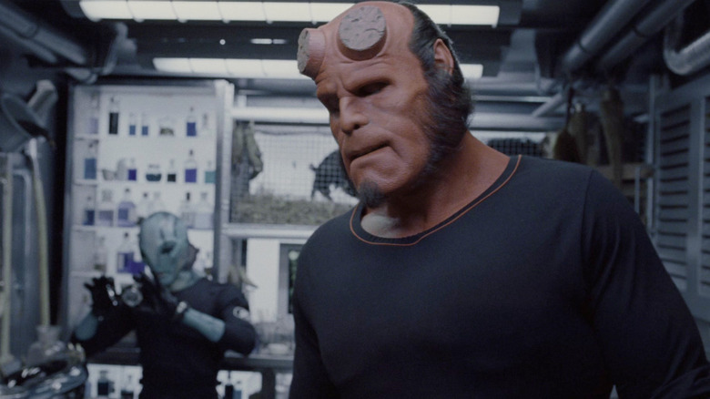 Ron Perlman's Hellboy squints while Doug Jones' Abe Sapien works in the background in Hellboy (2004)