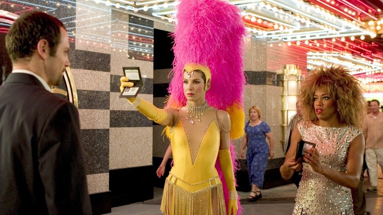 Gracie e Sam em roupas de Showgirl mostrando seus IDs em Miss Congeniality 2: Armado e Fabuloso