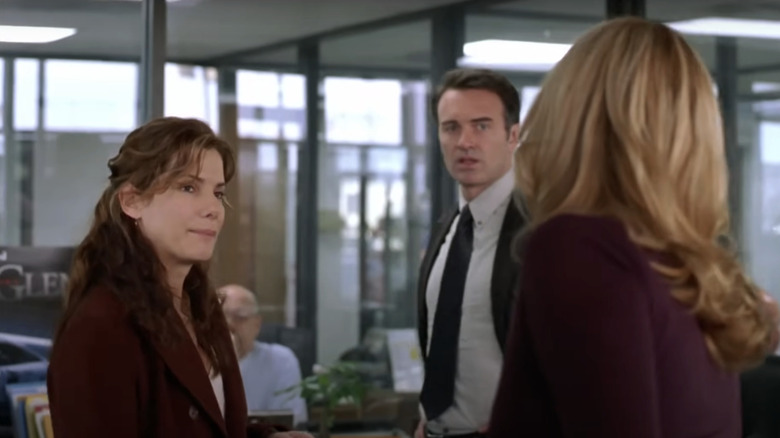 Linda Hanson dari Sandra Bullock berdiri dekat dengan James Hanson dari Julian McMahon di sebuah kantor di Premonisi