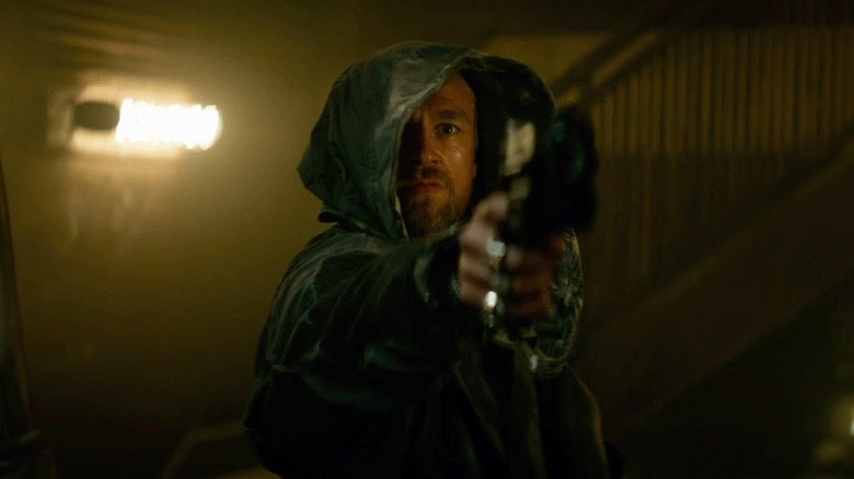 Charlie Hunnam in Rebel Moon aiming a handgun