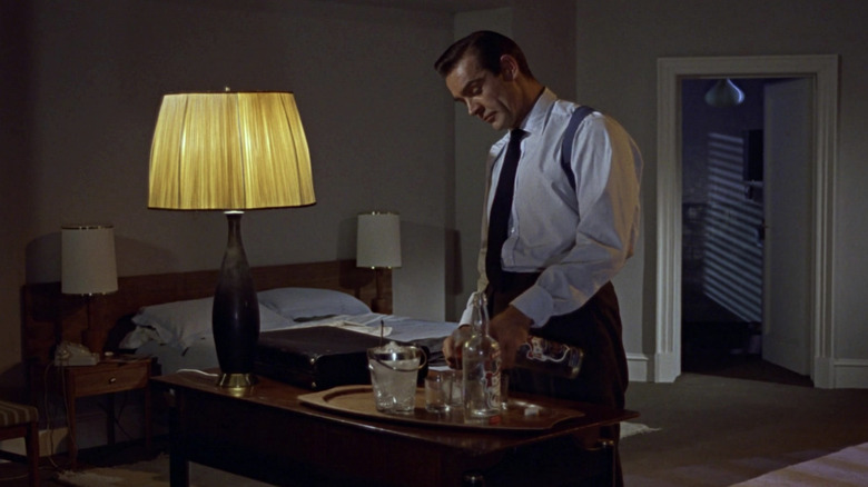 James Bond dari Sean Connery menuangkan minuman di kamar hotelnya di Dr No