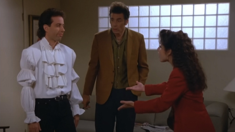 Jerry mengenakan kemeja bajak laut, sementara Kramer memperhatikan dan Elaine memohon padanya di Seinfeld