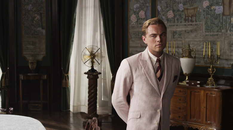 Jay Gatsby, looking stern, standing in a rich bedroom