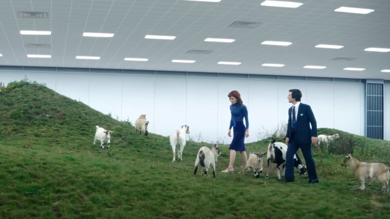 Adam Scott as Mark S. and Brit Lower as Helly R. walking through a group of goats in Severance