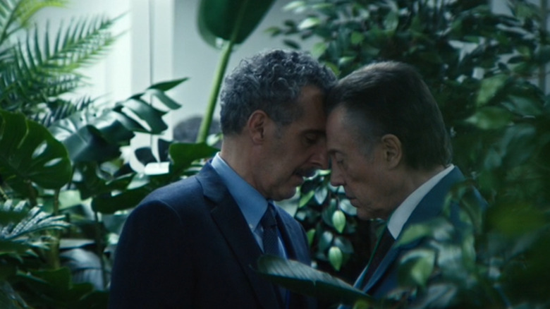 John Tourouror in the role of Irving B. and Christopher Wals in the role of Berto G. sharing an intimate moment in a room full of greens in 1 season severrant