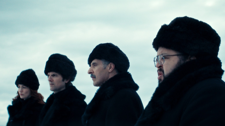 Helly, Mark, Irving, and Dylan wearing coats and hats and standing outside against a grey/blue sky in Severance season 2