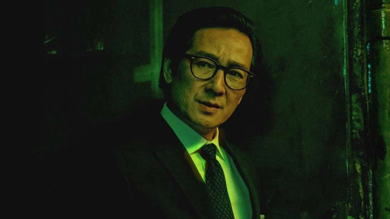 a man in a suit with glasses in a dark corner